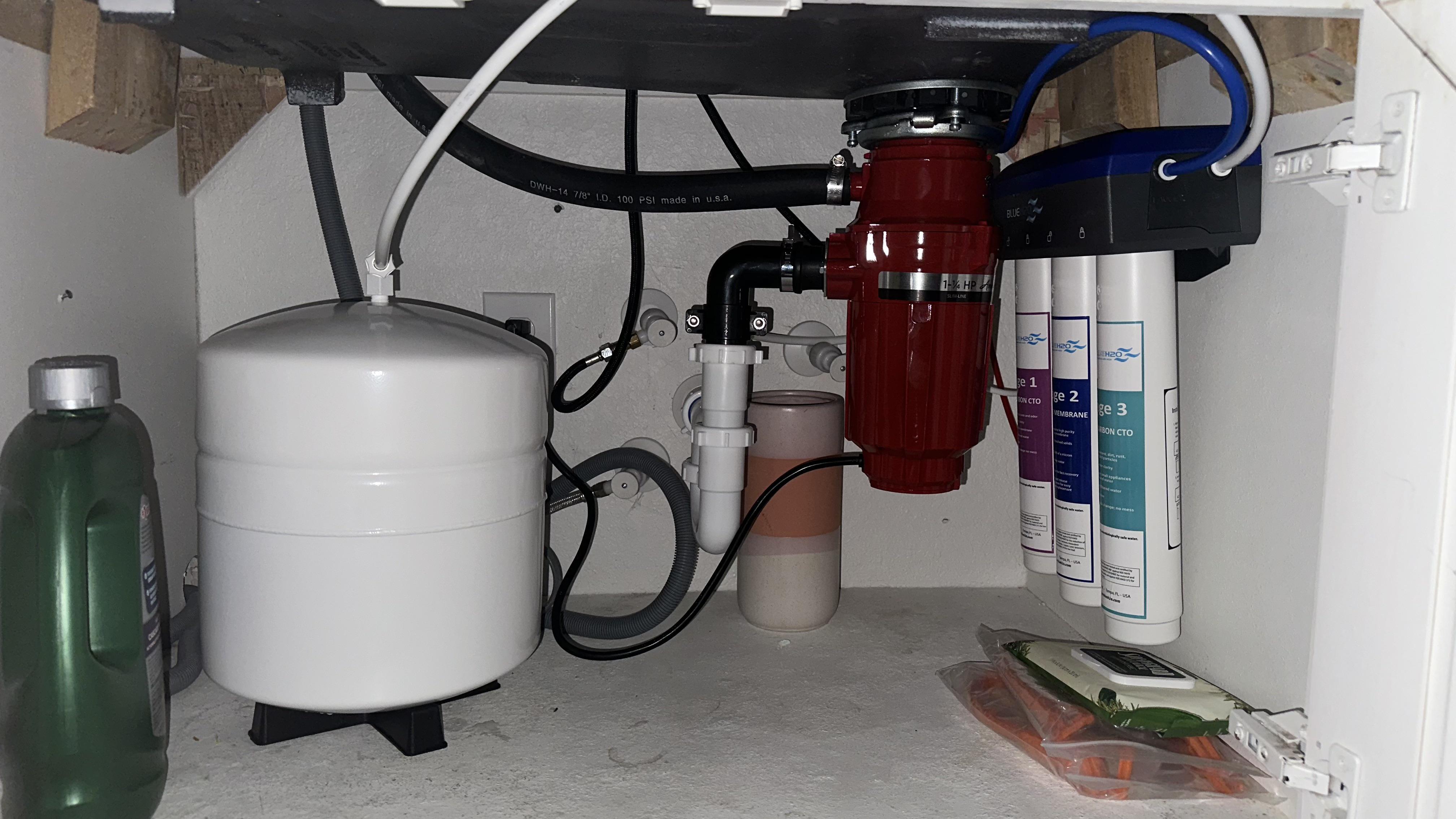 Under-sink garbage disposal unit and water filtration system installed in a kitchen
